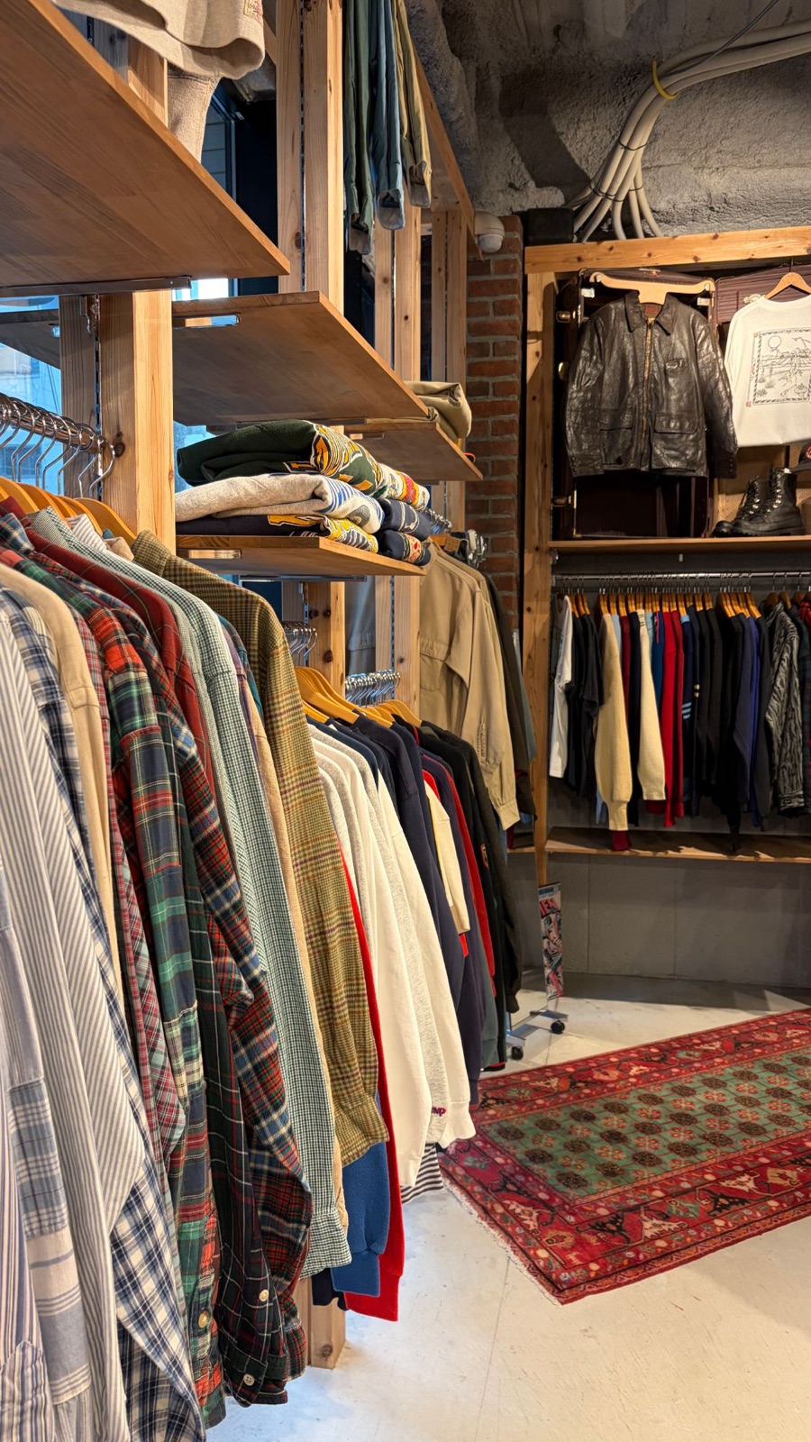 古着屋さんの店内。チェックシャツやスウェットがずらりと並ぶ